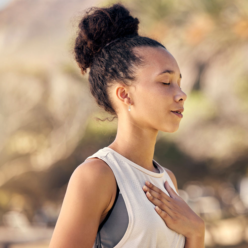 Black woman, breath and hand on chest, for meditation and wellness being peaceful to relax. Bokeh, African American female and lady outdoor, in nature and being calm for breathing exercise and health.