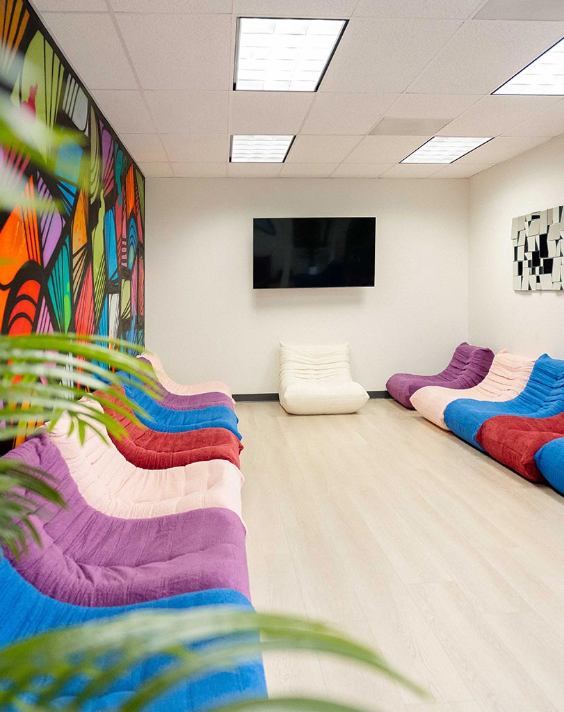 Lounge with pink and purple seating and tropical plants at Lotus Recovery