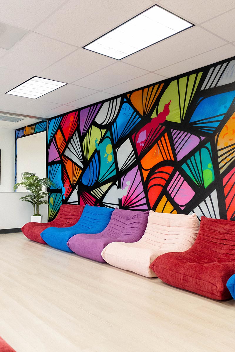 Lounge with red seating and a stained-glass style mural at Lotus Recovery