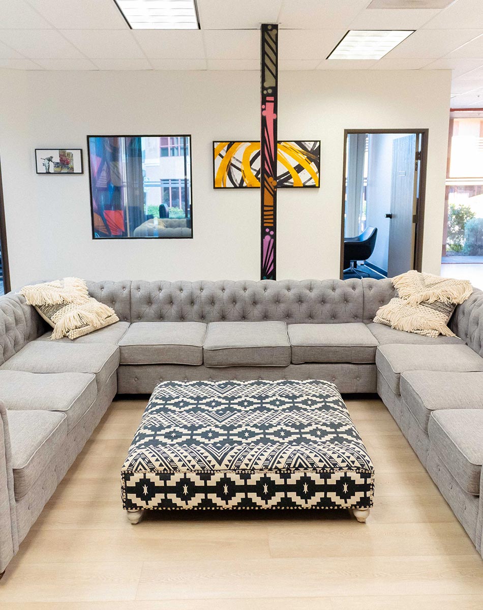 Lounge with a gray sectional and patterned ottoman at Lotus Recovery